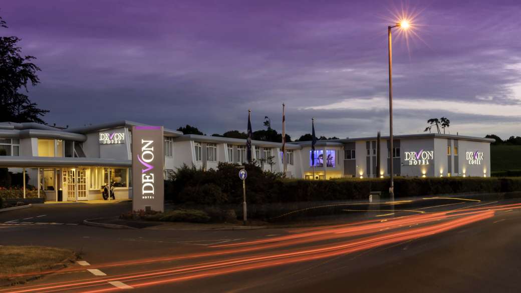Devon Hotel Exterior with Sign and Flags at Night