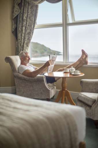 Royal Duchy Hotel Sea View Room Accommodation with Guest Relaxing and Reading Newspaper