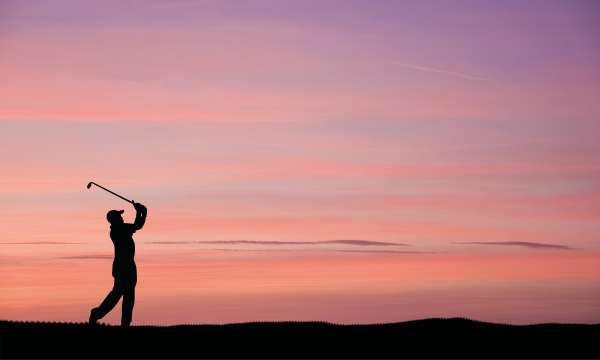 Golfer mid swing in sunset
