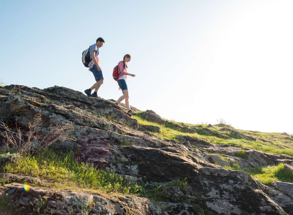 A couple walking down a rocky hill on a countryside hike
