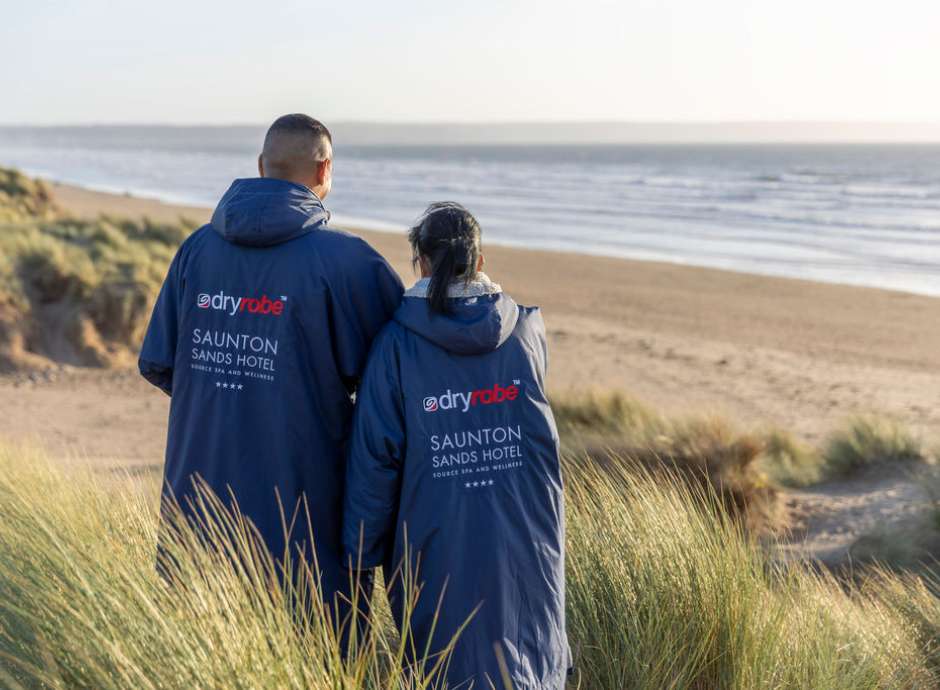 Couple standing on the beach with their branded Saunton Sands Hotel dryrobes on