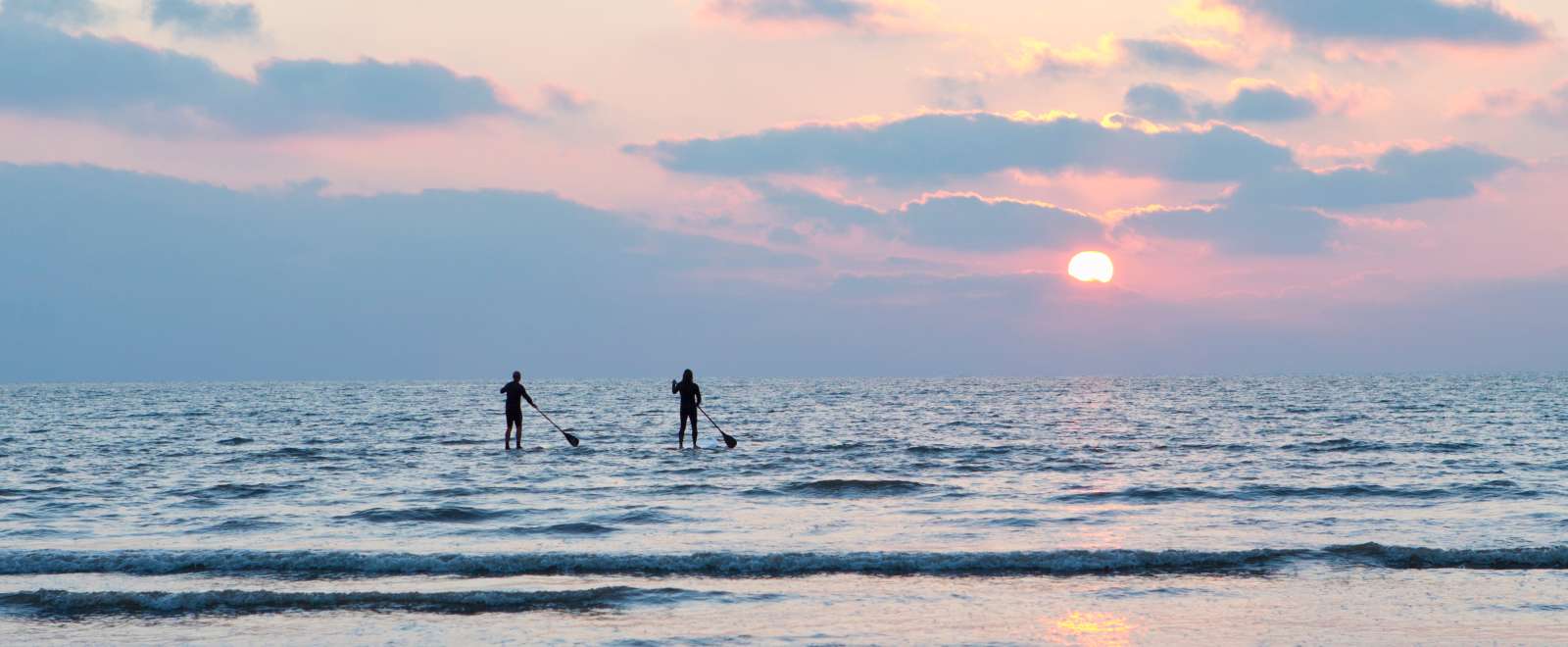 Two paddle boarders in the winter