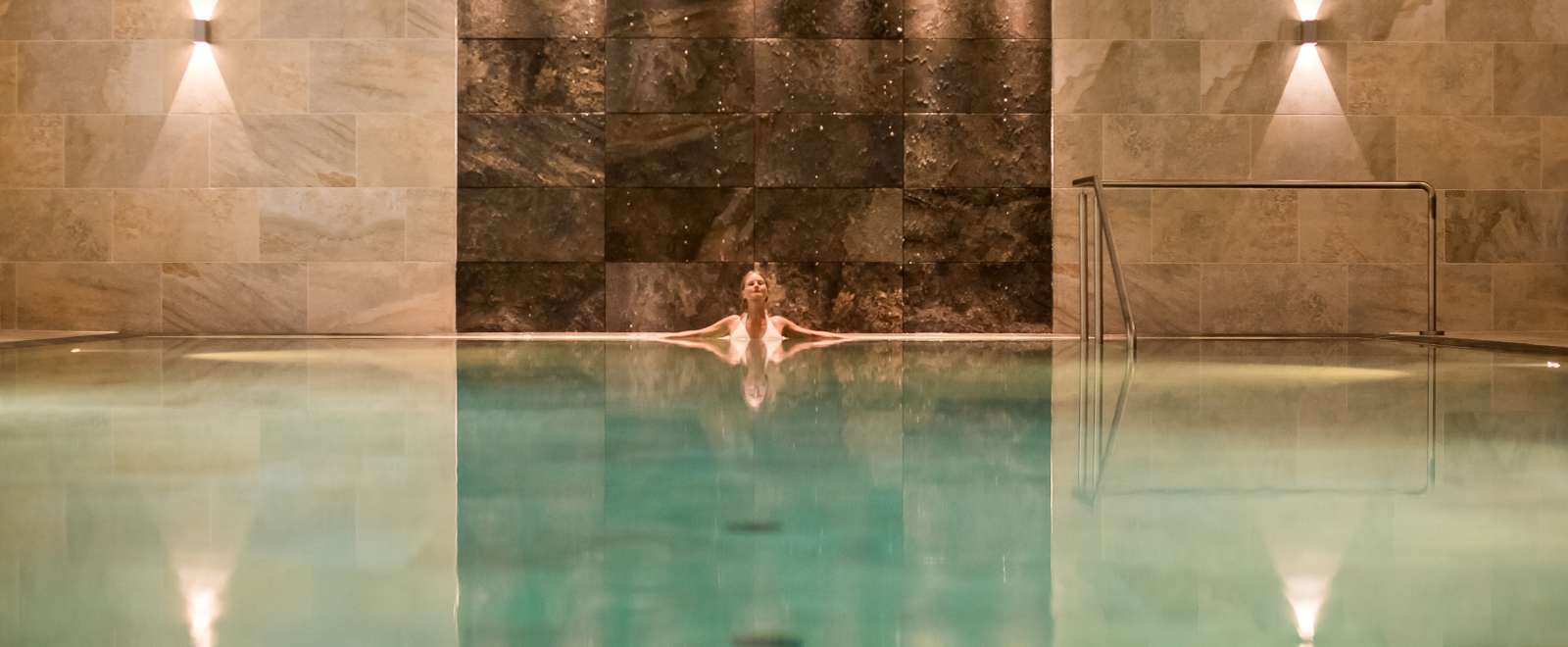 woman in source spa indoor pool relaxing at the end under lights