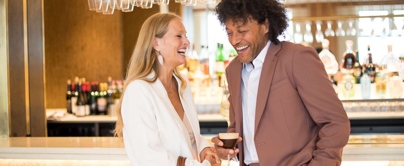 couple laughing in terrace bar with cocktail