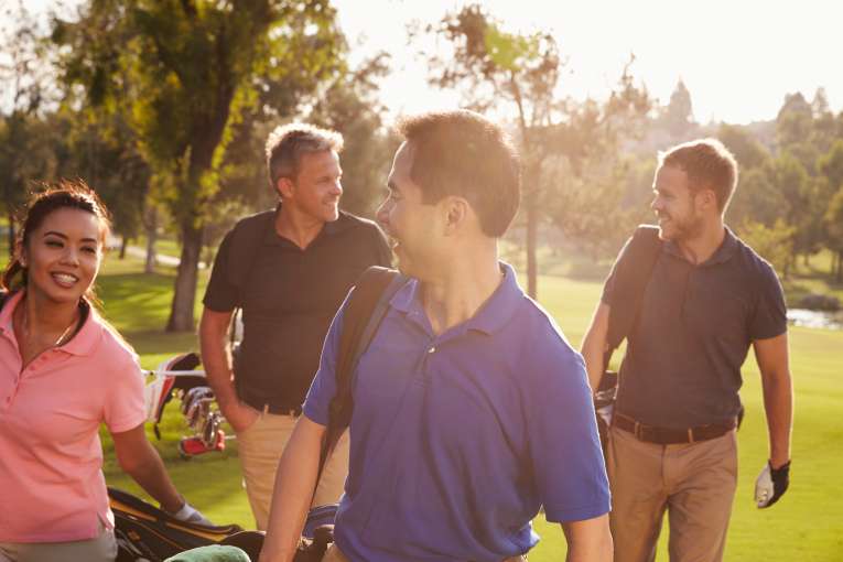 A group of happy golfers walking on the green