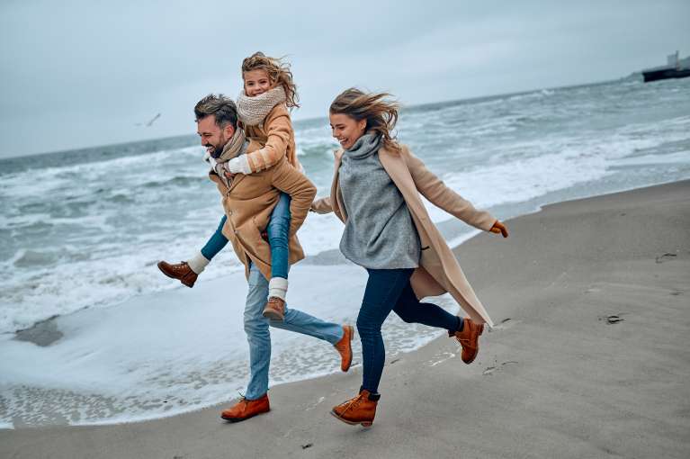 A family running across a beach in the winter