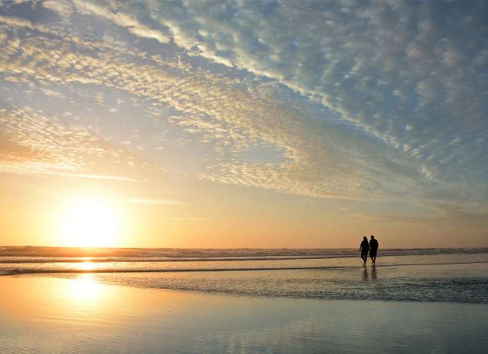 Couple walking along a beach in winter at Sunset