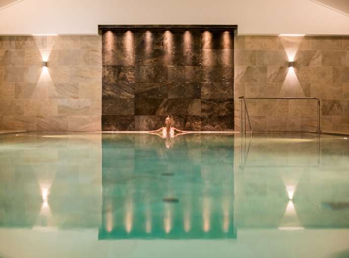 woman in source spa indoor pool relaxing at the end under lights