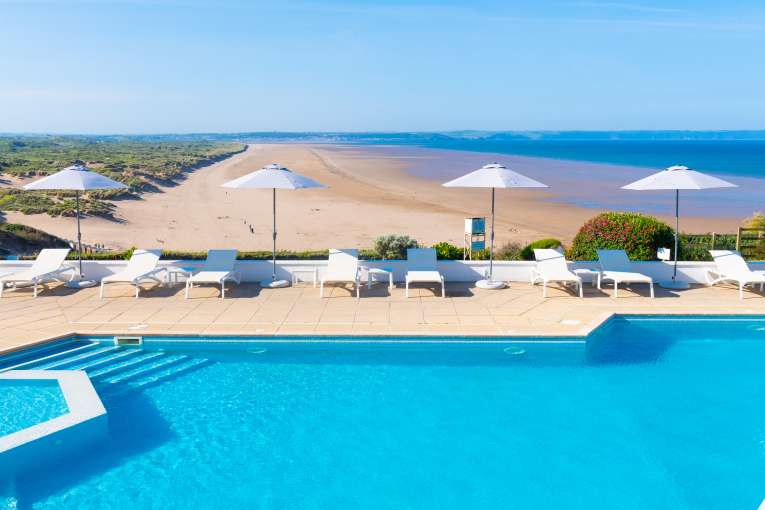 Outdoor pool with parasols overlooking the beach