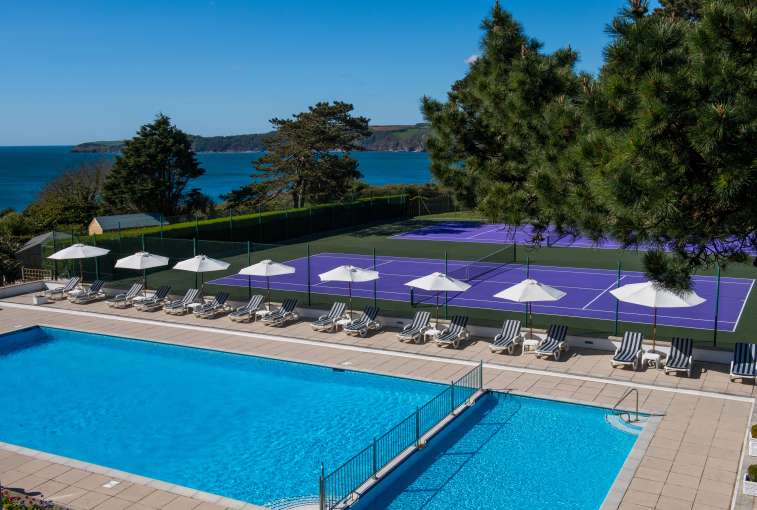 Swimming pool and tennis courts on a sunny day at the Carlyon Bay Hotel