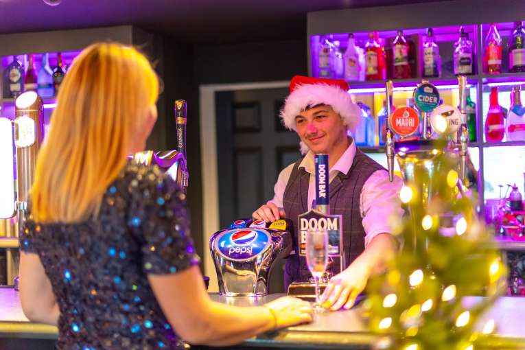 Woman in sparkly dress buying Prosecco from festive bar man
