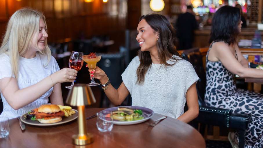 2 young woman enjoying drinks and food at 62 the bank