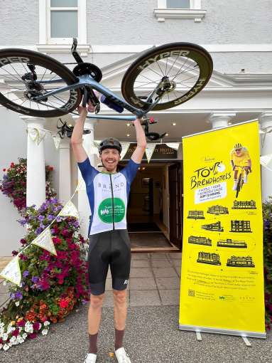 Aidan lifting bike in the air outside The Royal Duchy Hotel