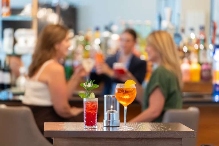 Ladies having a cocktail at the bar with staff behind them at The Royal Duchy Hotel 