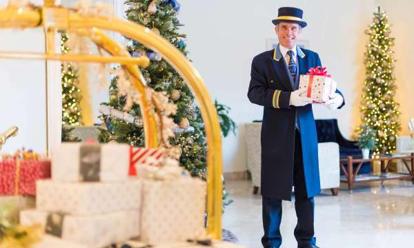 Royal Duchy Hotel Doorman with Presents by Christmas Tree