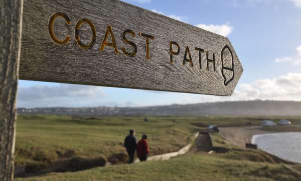 A coast path sign with a couple in the background