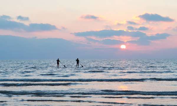 Two paddle boarders in the winter