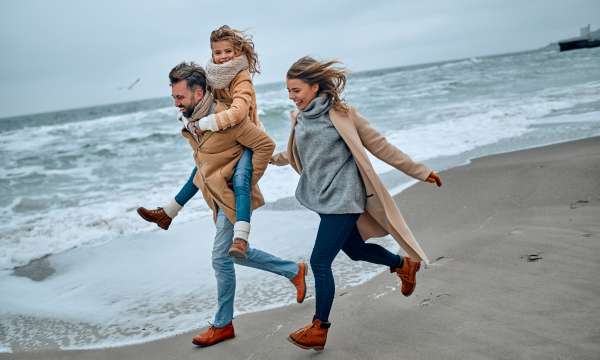 A family running across a beach in the winter