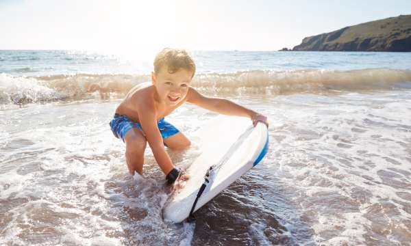 A young boy with a bodyboard in the shallows on the beach