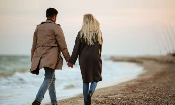 A couple walking hand in hand along a beach in winter