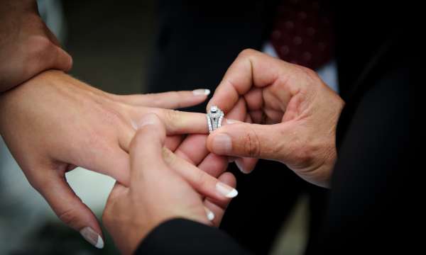 Man putting engagement ring on his fiancees finger
