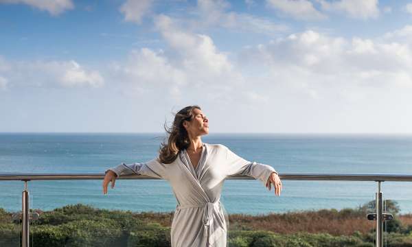 Woman on balcony with sea in background relaxing