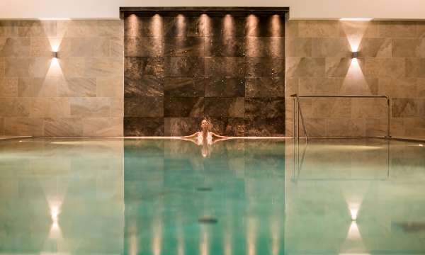woman in source spa indoor pool relaxing at the end under lights