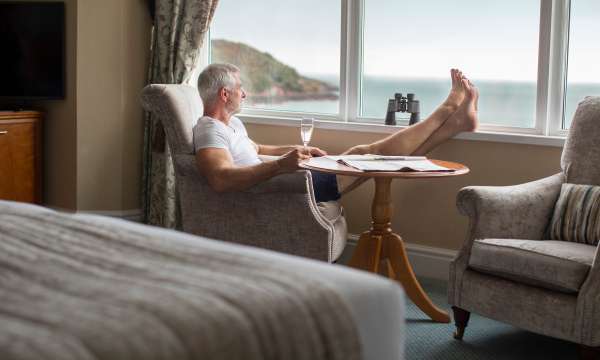 man relaxing with feet up sea view room with prosseco