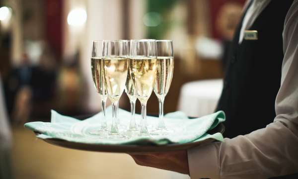 waiter carrying glasses of champagne on a tray