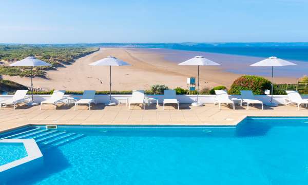 Outdoor pool with parasols overlooking the beach