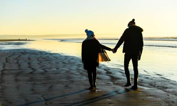 Couple walking on the beach during winter, hand in hand