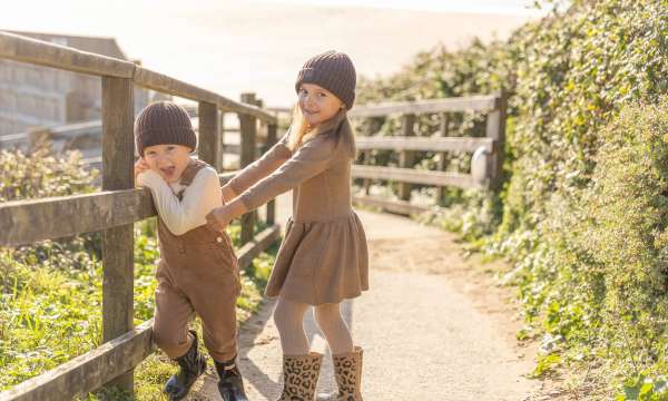 Two young children walking down the path to the beach 