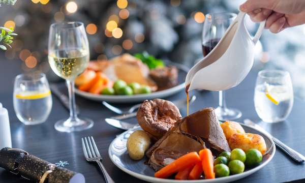 Person pouring gravy on Festive roast dinner