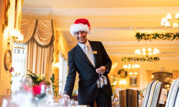 Imperial Hotel Staff Member Wearing Santa hat and Setting up Table for Christmas Party