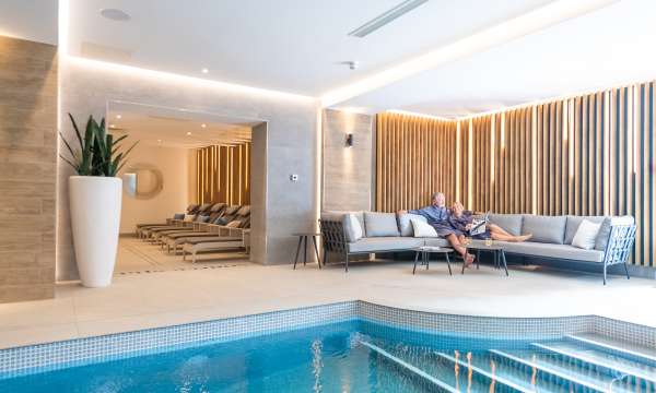 Couple relaxing on sofa by indoor pool