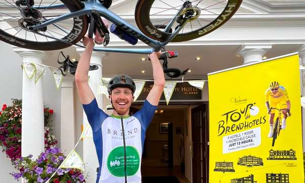 Aidan lifting his bike in the air outside the Royal Duchy Hotel