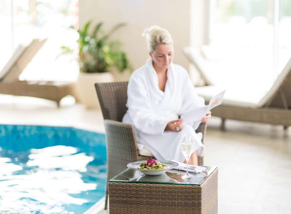 Carlyon Bay Hotel Woman in Robe Sitting by Indoor Pool with Salad and Champagne