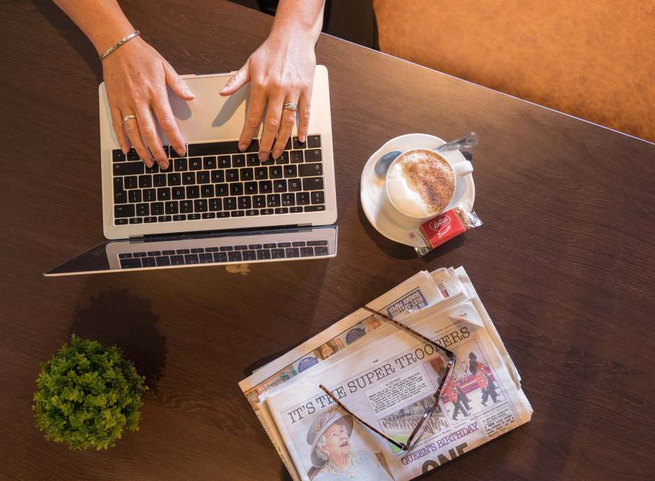 Devon Hotel Woman Typing on Laptop with a Coffee