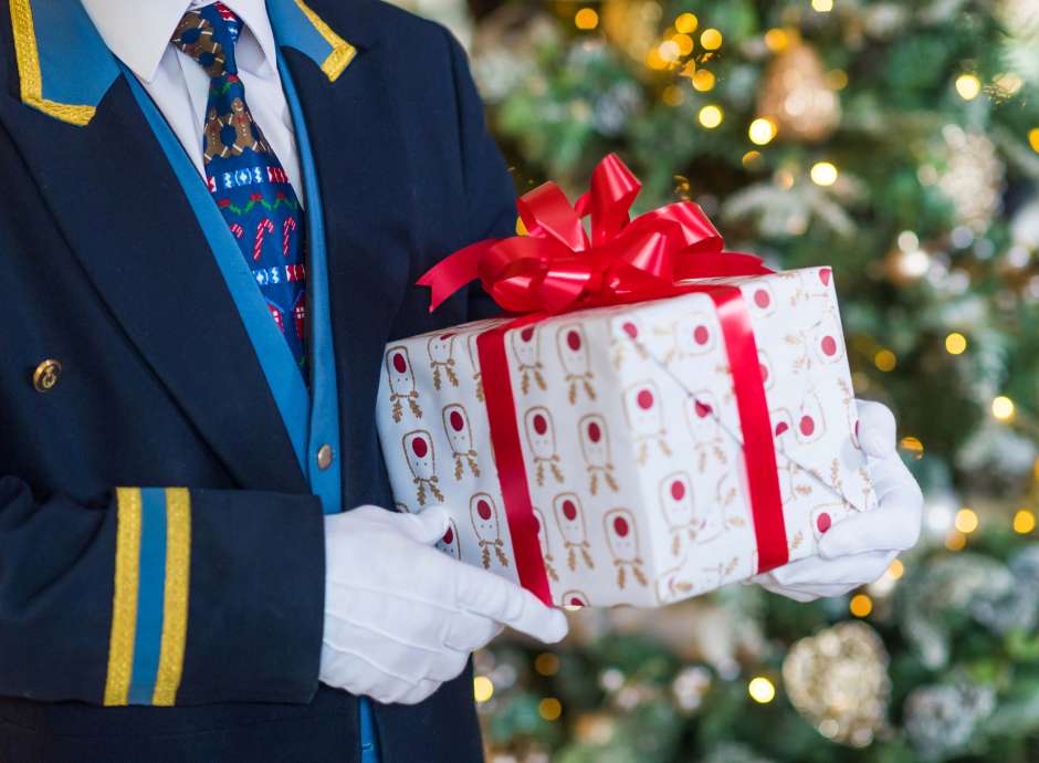 Royal Duchy Hotel Doorman with Festive Tie Holding Christmas Present