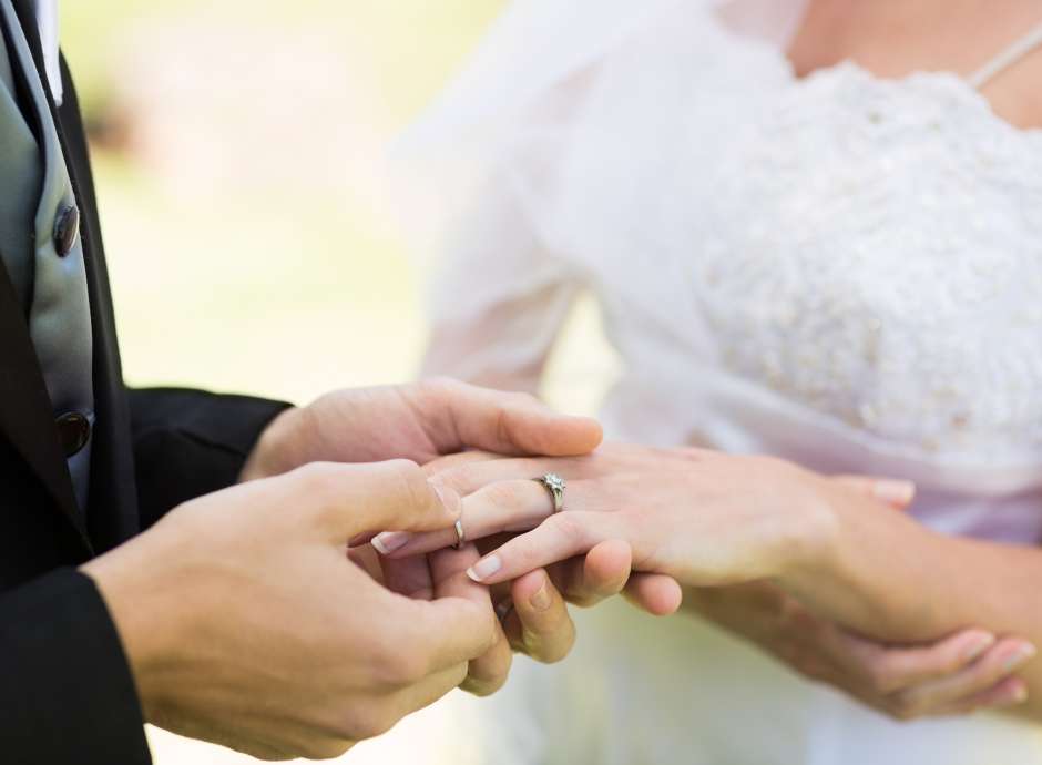 Groom putting wedding ring on the Brides finger