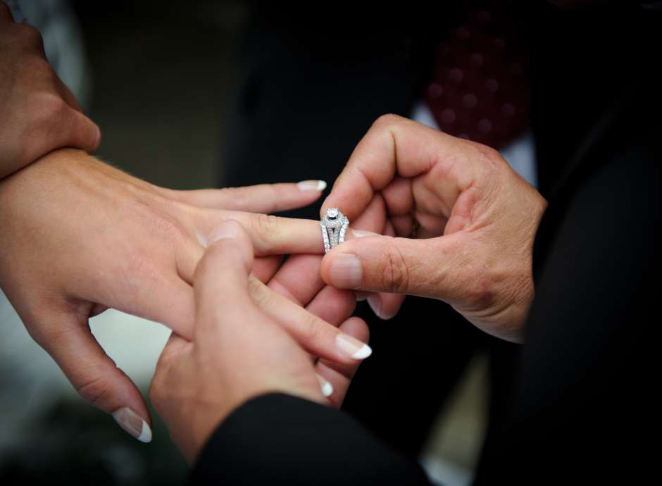 Man putting engagement ring on his fiancees finger