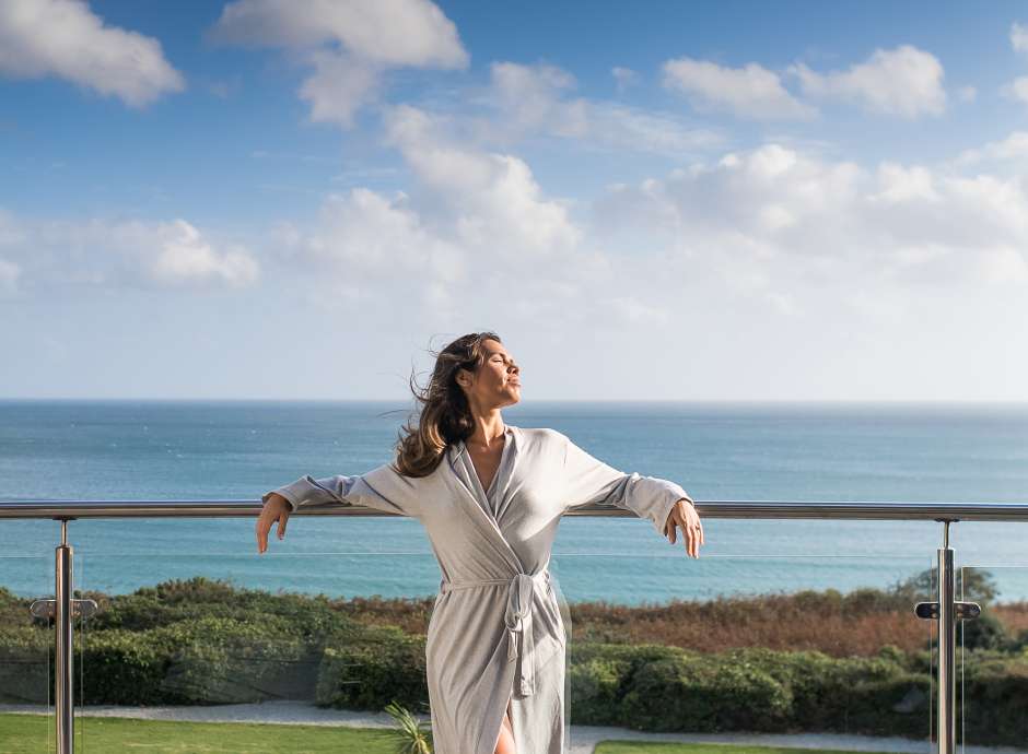 Woman on balcony with sea in background relaxing