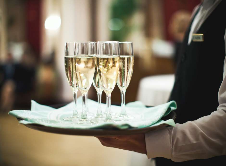 waiter carrying glasses of champagne on a tray