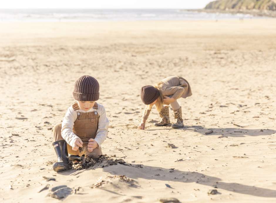 Two children on the beach during autumn playing with the sand 