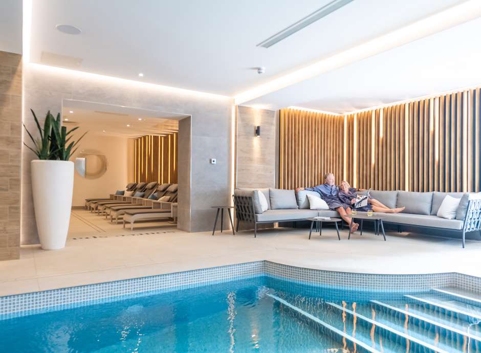 Couple relaxing on sofa by indoor pool