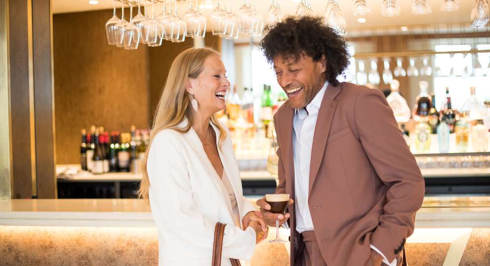 couple laughing in terrace bar with cocktail